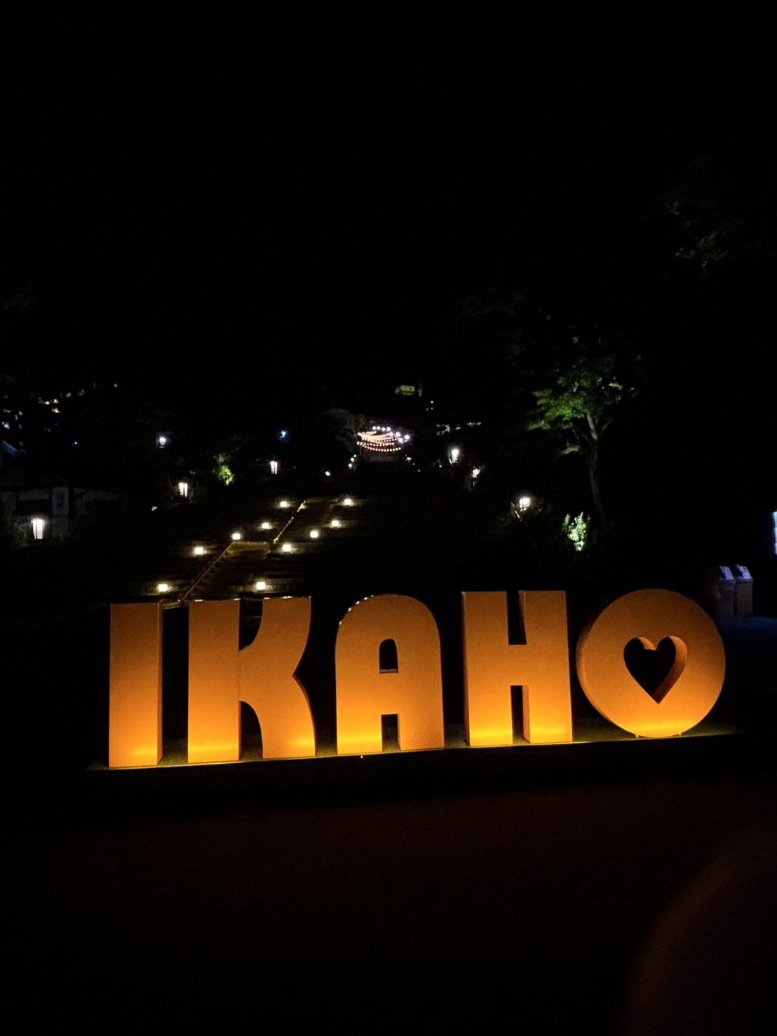 夜に光る「IKAHO」の文字と、その奥の石段