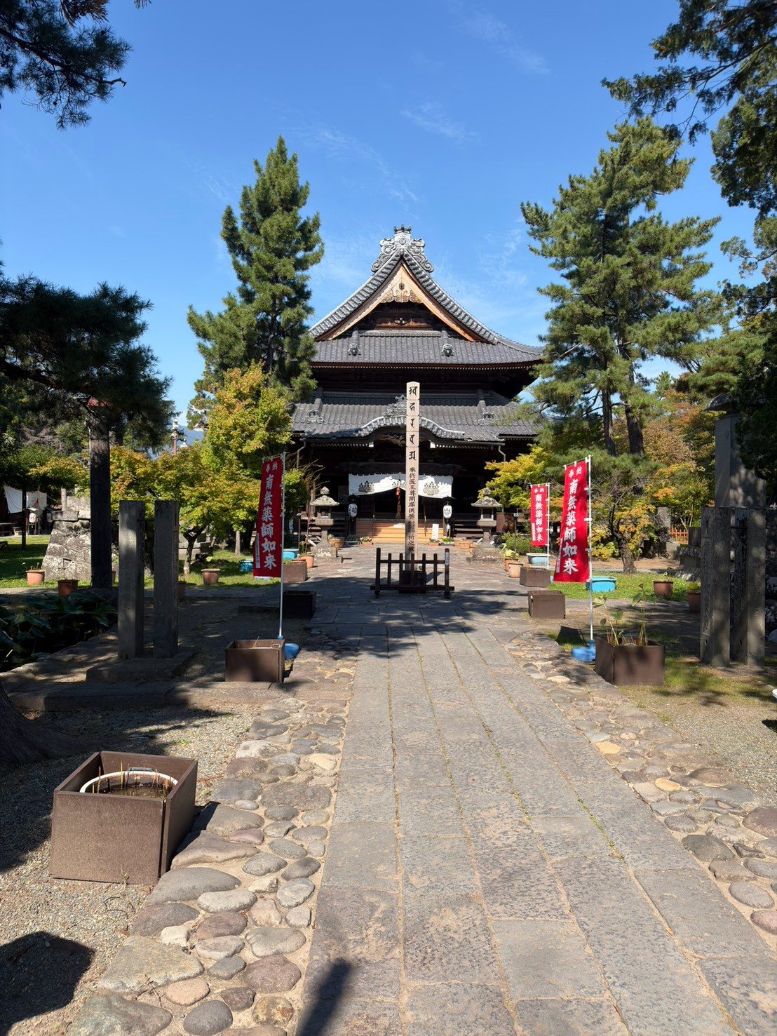 松の木にかこまれたお寺の本堂と、石畳の参道