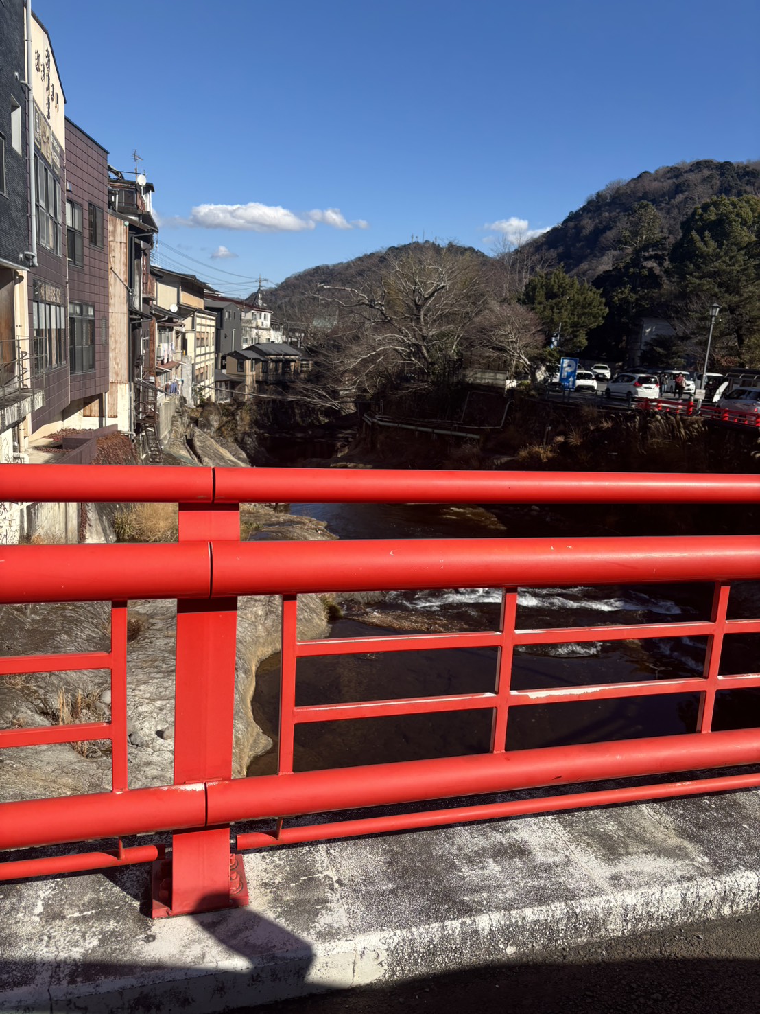 赤い欄干の橋の上から見た、桂川と温泉の町並み